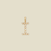 A gold initial pendant charm shaped like the letter 'I', adorned with small clear gemstones, centered on a solid beige background.
