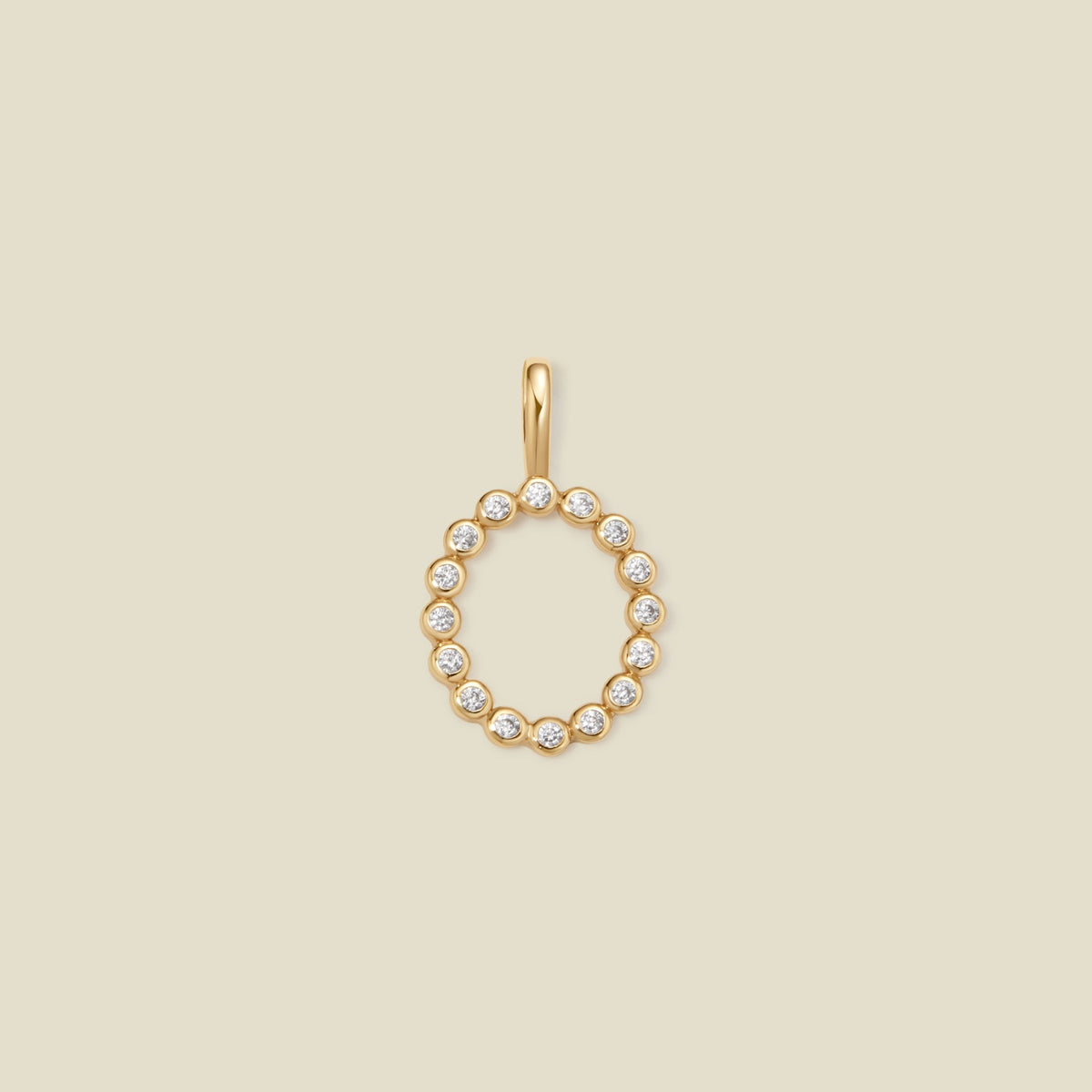 A gold initial 'O' charm featuring small clear round-cut stones, set against a solid light beige background.