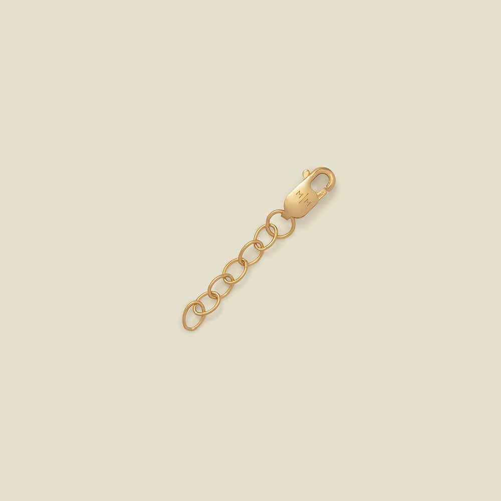 A gold-toned lobster clasp connected to a short chain of oval links, photographed on a plain warm beige background.