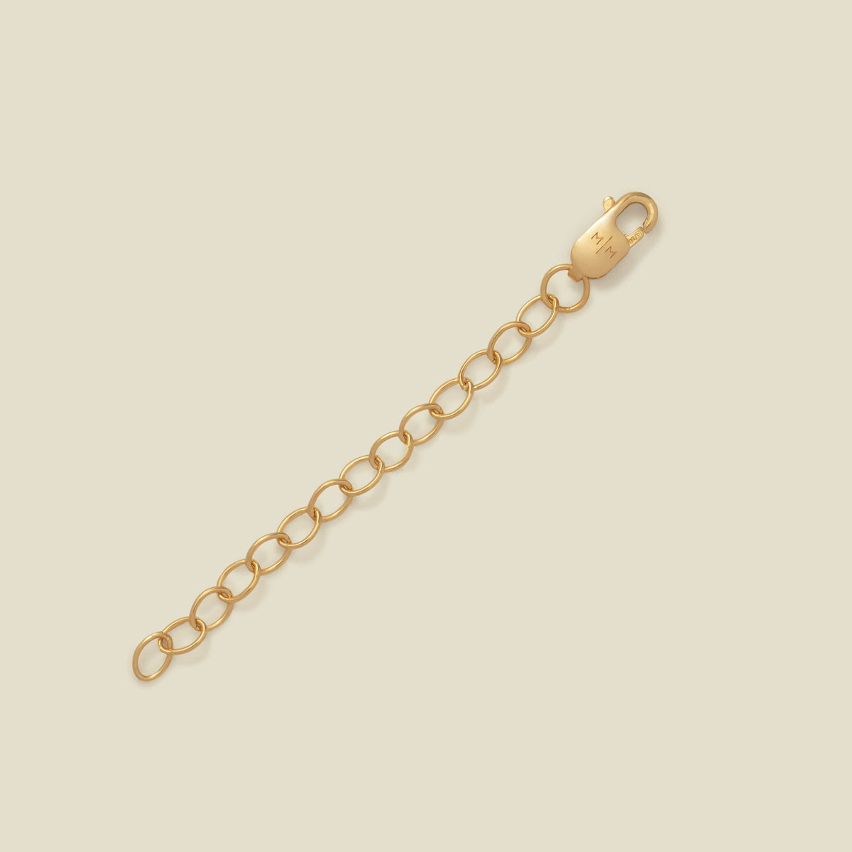 A gold-toned lobster clasp connected to a short chain of oval links, photographed on a plain warm beige background.