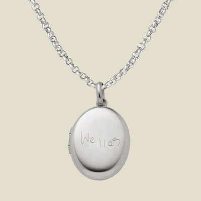 Silver locket necklace with 'Welles' engraving on a beige background