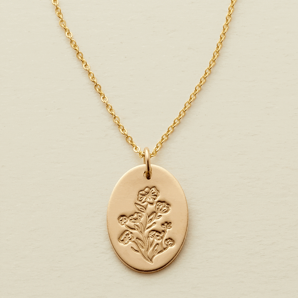 A gif of a delicate gold pendant chain necklace with a flat oval disc charm, showcasing an engraved floral pattern with different numbers of flowers being added and removed from the disc.