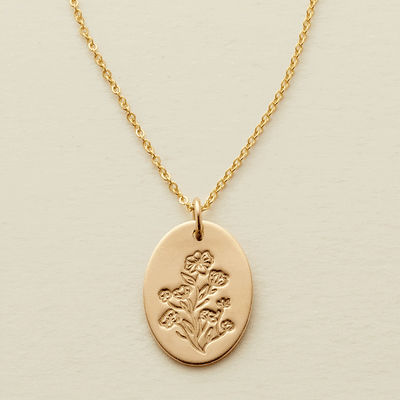 A gif of a delicate gold pendant chain necklace with a flat oval disc charm, showcasing an engraved floral pattern with different numbers of flowers being added and removed from the disc.
