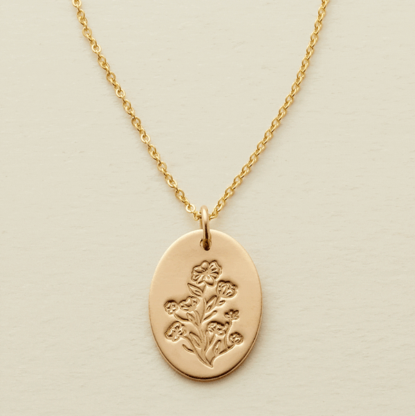 A gif of a delicate gold pendant chain necklace with a flat oval disc charm, showcasing an engraved floral pattern with different numbers of flowers being added and removed from the disc.