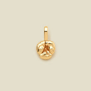 A small gold violet flower charm, shown on a solid light beige background.