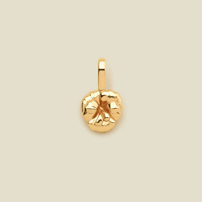 A small gold violet flower charm, shown on a solid light beige background.
