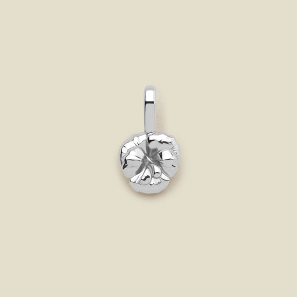 A silver violet flower charm, shown on a solid light beige surface.