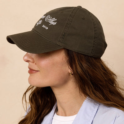 A profile image of a woman wearing a green cap with text on a beige background