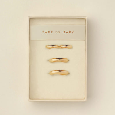 Two pairs of polished wide gold hoops, one smaller and one larger, displayed in a cream-colored presentation box with the brand name 'MADE BY MARY' printed on the insert.