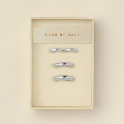 Two pairs of polished wide silver hoops, one smaller and one larger, displayed in a cream-colored presentation box with the brand name 'MADE BY MARY' printed on the insert.