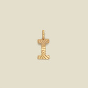 A small gold I-shaped charm with a textured, sunburst striped pattern, shown on a solid light beige background.