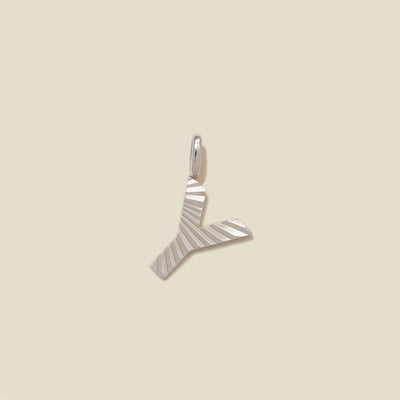 A small silver Y-shaped charm with a textured, sunburst striped pattern, shown on a solid light beige background.