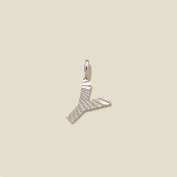 A small silver Y-shaped charm with a textured, sunburst striped pattern, shown on a solid light beige background.