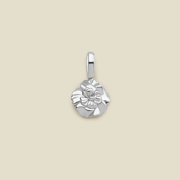 A polished silver flower charm pendant with a textured, layered petal design and a top loop, centered on a solid light beige background.
