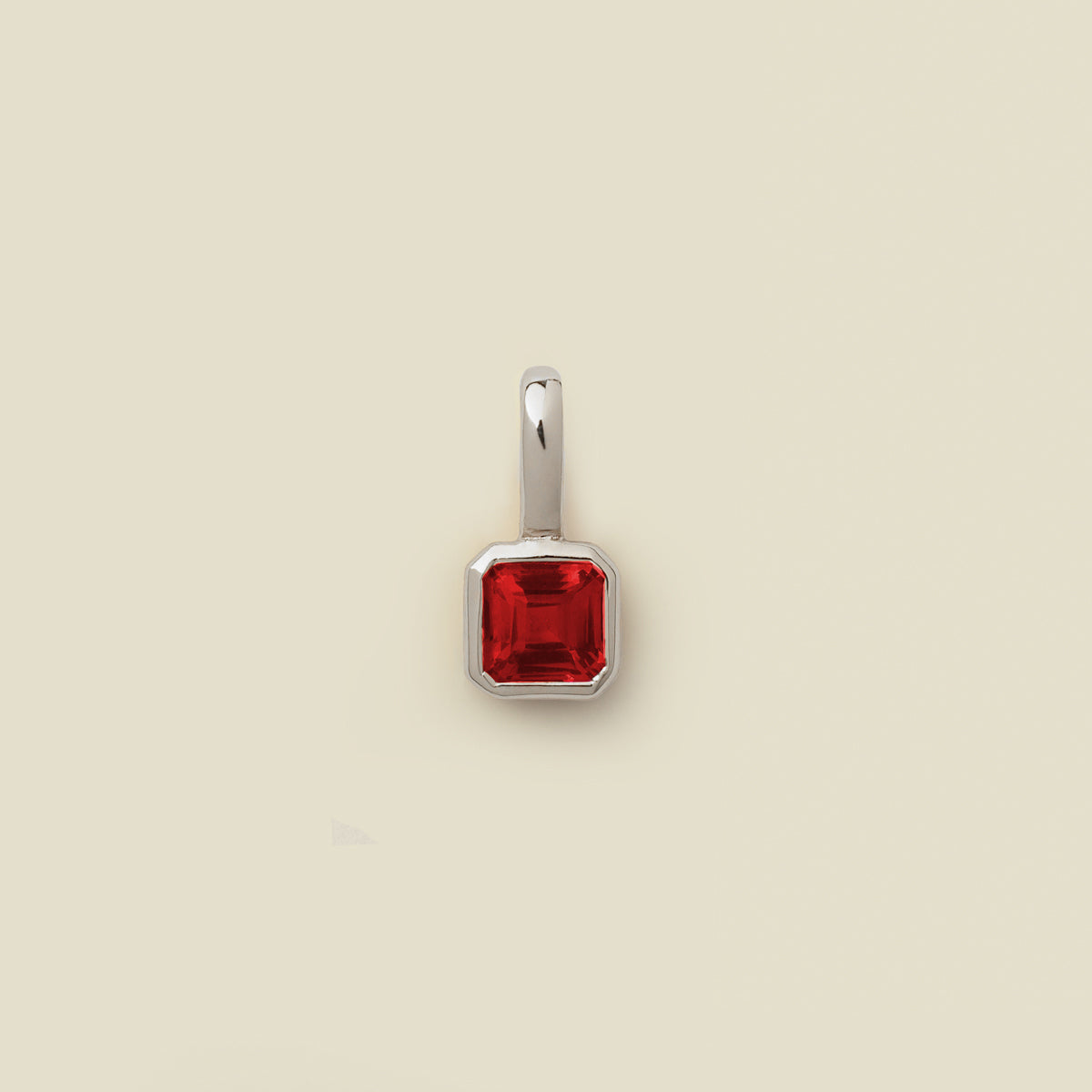 A square-cut red gemstone pendant in a polished silver bezel setting, centered on a solid light beige background.