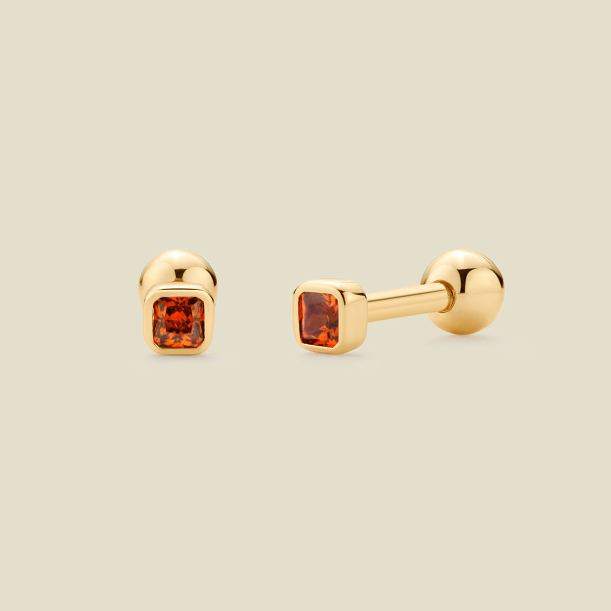 A pair of gold post earrings with square-cut red-orange gemstones, shown from front and side angles on a light beige background.
