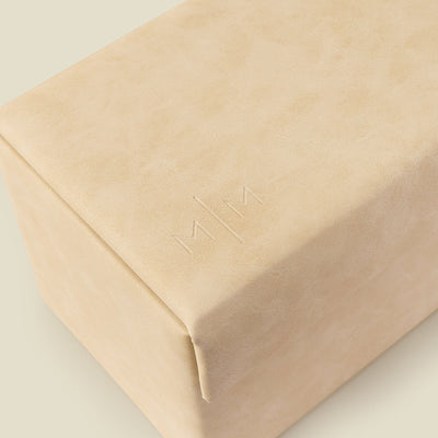 The edge of a cream colored rectangular jewelry box, showcasing an embossed 'M|M' logo.