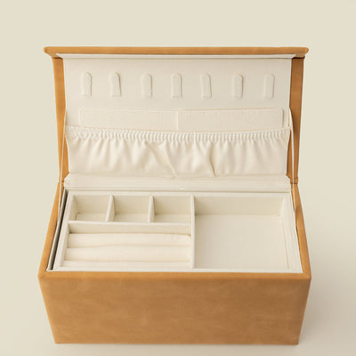 An open tan leather rectangular jewelry box, with small felt hooks and a large pocket on the lid, and multiple small square holding containers inside. 