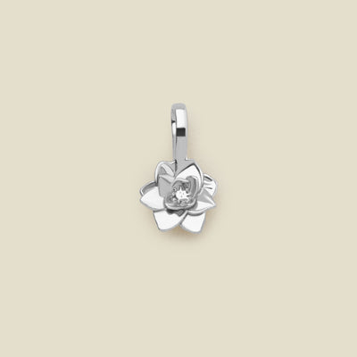 A polished silver lotus flower charm, shown against a solid light beige background.