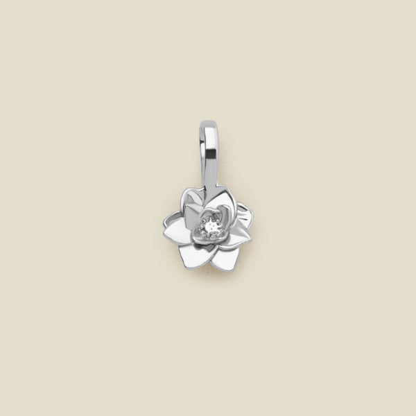 A polished silver lotus flower charm, shown against a solid light beige background.