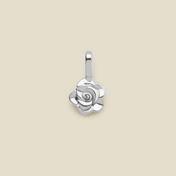 A small polished silver rose flower charm, shown on a solid light beige background.