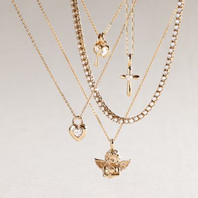 Gold necklaces with various pendants on a light gray background