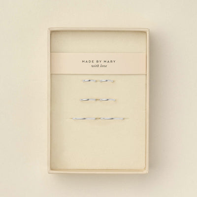 Six delicate silver wire hoop earrings displayed inside a cream-colored presentation box with a paper band reading 'MADE BY MARY with love'.