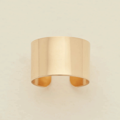 A minimalist, wide band ring in a polished gold finish, displayed against a clean, off-white background.