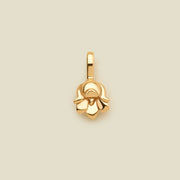 A polished gold lily of the valley flower charm, shown on a solid light beige background.