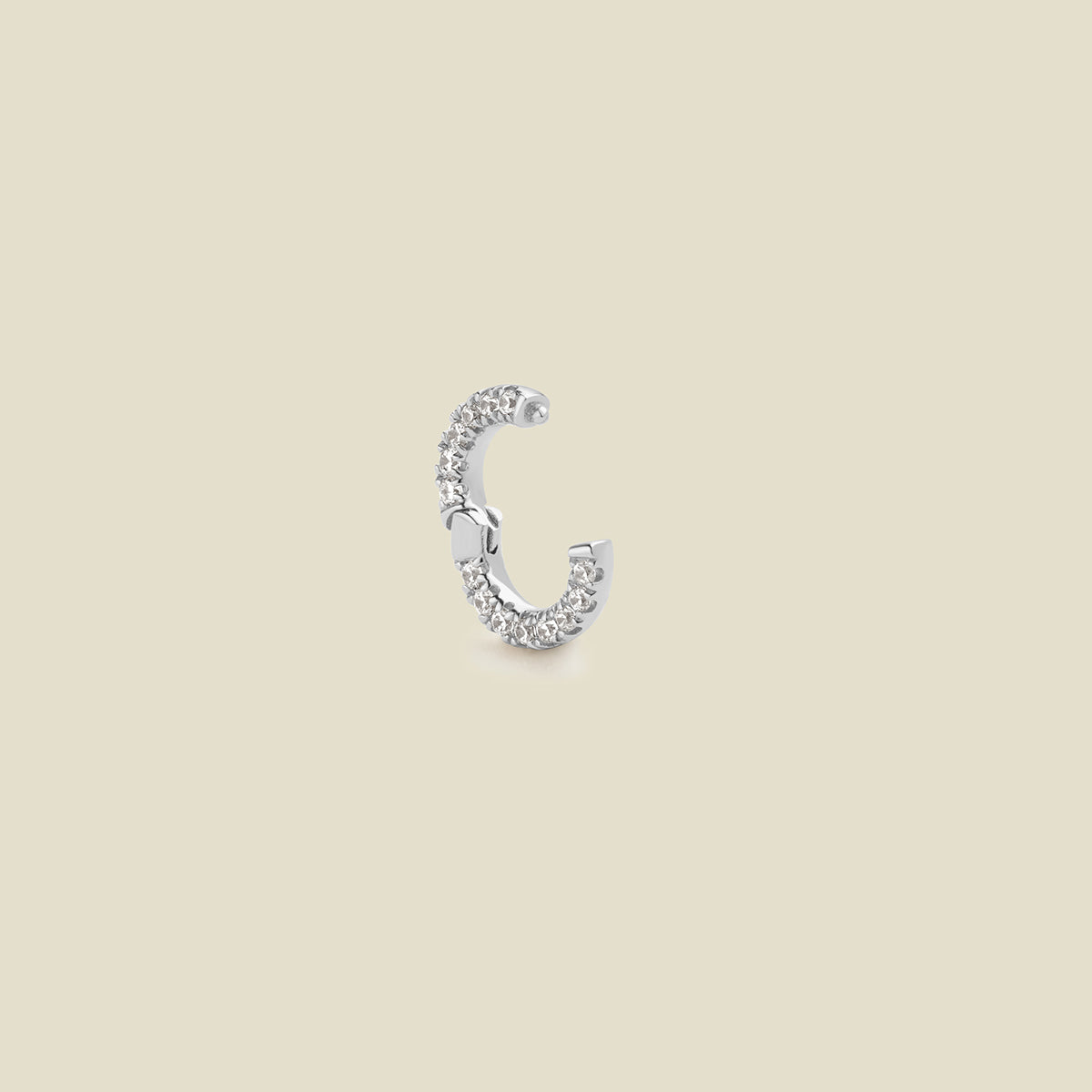 A small silver circular ring attachment embellished with clear pavé stones, shown with the latch open on a solid beige background.