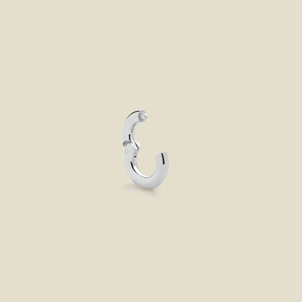 A polished silver round ring necklace attachment with an open latch mechanism, shown on a solid light beige background.