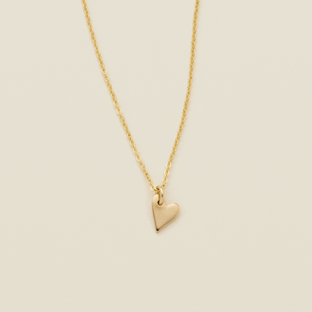 A gif of a delicate gold pendant chain necklace starting with a singular small gold heart charm, then adding more hearts to stack to the chain. Some of the hearts are engraved with single initials like 'A', 'M', and 'D'.