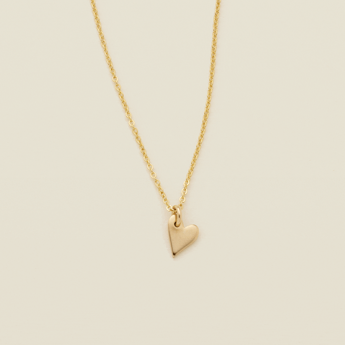 A gif of a delicate gold pendant chain necklace starting with a singular small gold heart charm, then adding more hearts to stack to the chain. Some of the hearts are engraved with single initials like 'A', 'M', and 'D'.