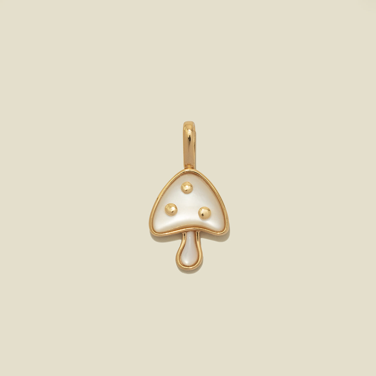 A small mushroom-shaped pendant charm with a gold-tone metal outline and a glossy white stone inlay, featuring three small gold dots on the cap, centered on a light beige background.