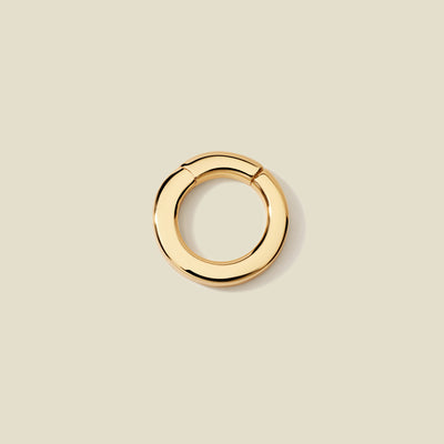 A polished gold round charm attachment for necklaces, set against a solid beige background.