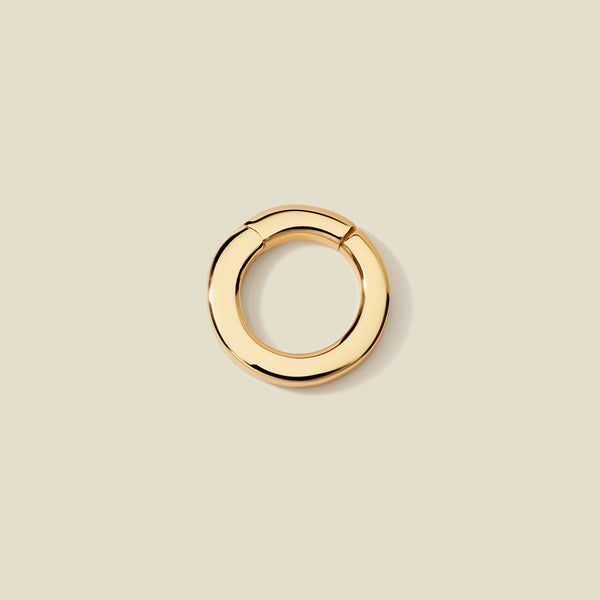 A polished gold round charm attachment for necklaces, set against a solid beige background.
