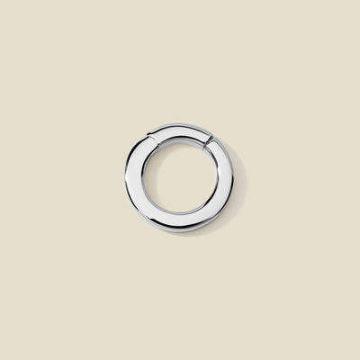 A polished silver round charm attachment for necklaces,  set against a solid beige background.