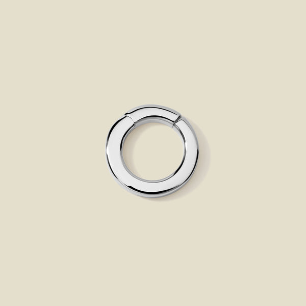 A polished silver round charm attachment for necklaces,  set against a solid beige background.