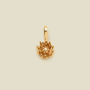 A small gold chrysanthemum flower charm, shown on a solid light beige background.