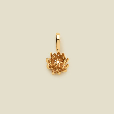 A small gold chrysanthemum flower charm, shown on a solid light beige background.