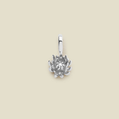 A small silver chrysanthemum flower charm, shown on a solid light beige surface.