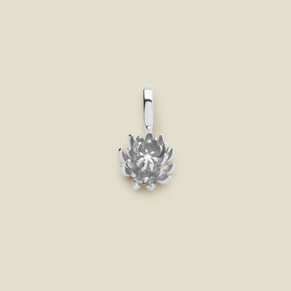 A small silver chrysanthemum flower charm, shown on a solid light beige surface.