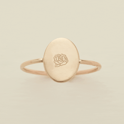 A gif of a dainty gold wire ring with a flat oval in the center, with different engraved designs cycling through one by one. There are initials and various floral motifs.