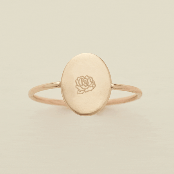 A gif of a dainty gold wire ring with a flat oval in the center, with different engraved designs cycling through one by one. There are initials and various floral motifs.