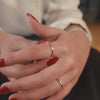 A short, close-up video of a woman putting on and playing with a gold, textured ring on her hand. 