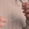 A short video of a person holding a silver heart link chain bracelet in both hands.