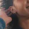 A short close-up lifestyle video of a woman showing off her ear with multiple earrings of varying shapes and sizes.