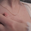 A short video of a person's neck wearing a delicate gold chain necklace featuring a short central segment of clear round and baguette-cut gemstones.