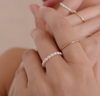 A close-up video of a person's hands showcasing different pearl and gold rings.