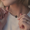 A short video of a blonde woman in a white t-shirt wearing a delicate gold pendant chain necklace with a round disc engraved with the letters 'K' and 'J' separated by a heart.
